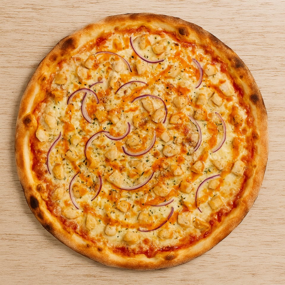 Roma Pizza's chicken pizza with red onions, cheese, and a drizzle of sauce on a wooden surface.