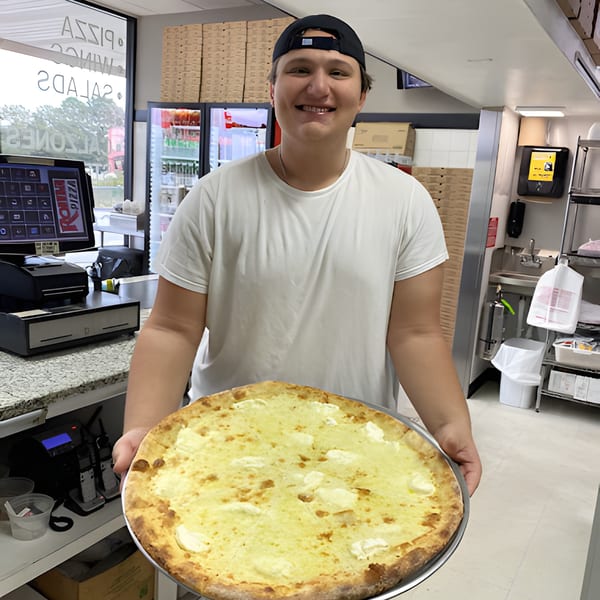 A smiling Roma Pizza employee holds a large, freshly baked white pizza with ricotta cheese.